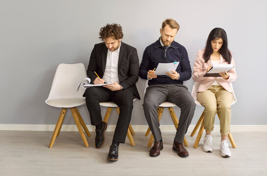 Candidates await interview, applicants fill assessment paperwork. In a bright office lobby they wait for recruitment decisions after testing for a vacancy. Clear concept of hiring and talent.
