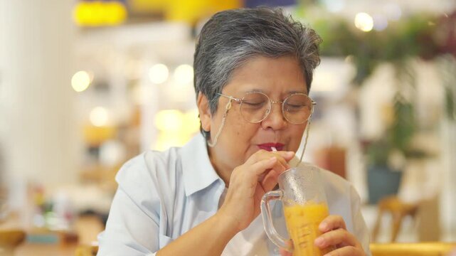 Happy Asian senior woman travel and shopping in the city on summer holiday vacation. Group of Healthy elderly women friends enjoy outdoor lifestyle having lunch eating food together at restaurant.
