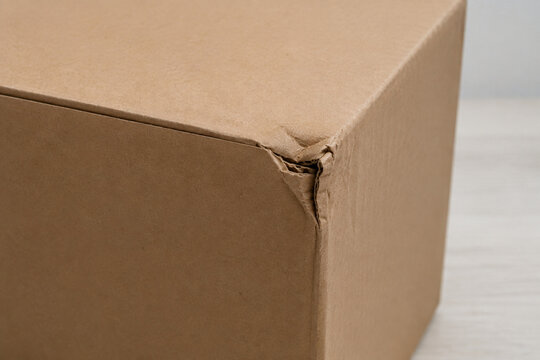 Crushed corner and torn corrugated cardboard on a parcel box