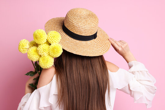 Woman with beautiful dahlia flowers on pink background, back view