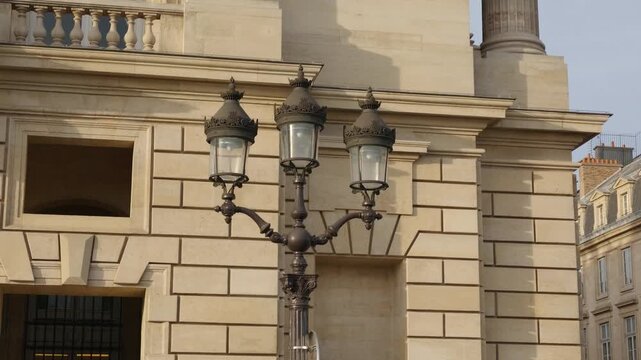 Ornate street lamp standing against a traditional stone building facade in Paris, France
