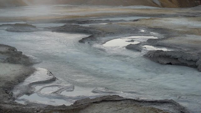Geothermal mud pool with water flowing steadily across it