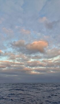 Vertical seascape at sunset with calm ocean water and pastel cloudy sky, featuring a subtle heart-shaped cloud