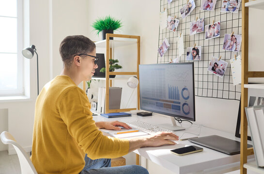 Freelancer man analyst at home office computer. Reviewing analytics on screen, tracking finance data and planning monthly budget with notes. Concept is financial planning and analytics.