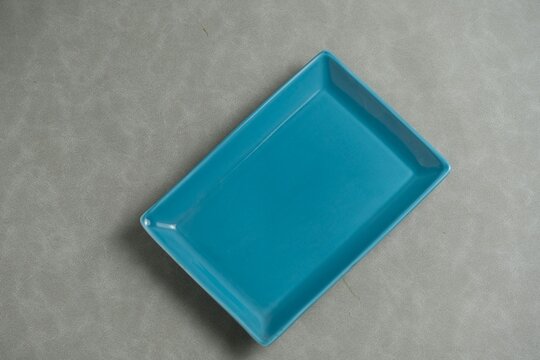 Empty rectangular blue ceramic plate isolated on a grey background, top angle view. Piring persegi