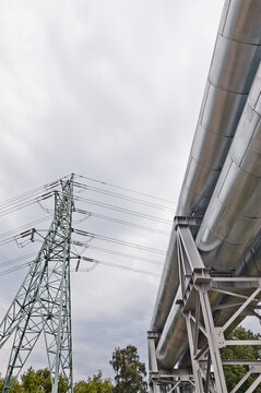 a pipeline and a power transmission tower against a gray sky