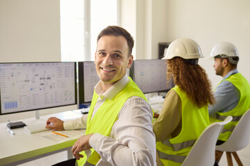 Obraz na płótnie Canvas Engineers operators controlroom monitoring industry safety analysis technology. Supervisor in high visibility vest works while the team monitors dashboards. Team ensures safe reliable operations.