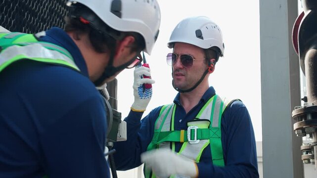 Technician team checking pipe valve, industrial maintenance service monitoring cooling tower system, two man engineer using walkie talkie radio, technical inspection, industry concept.
