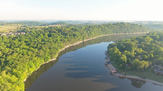 Aerial footage captures a winding river surrounded by vibrant green trees and rolling hills, highlighting the peaceful natural beauty of Johnson City, Tennessee, with clear reflections on the water