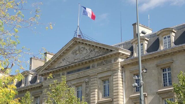 French flag flying above a classical building in Paris, France, on a clear day