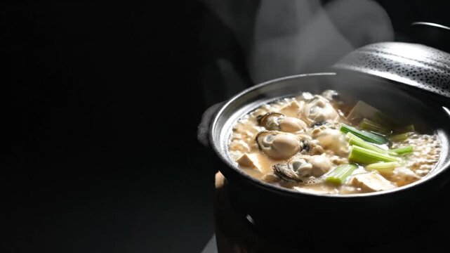 Japanese oyster hot pot kaki nabe simmering in ceramic clay pot with tofu and scallions on dark background