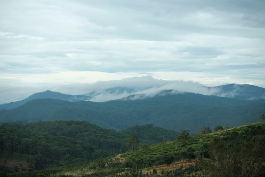 Landscape of rolling mountains with clouds swirling over mountain peaks after rain in Cau Dat Da Lat Vietnam