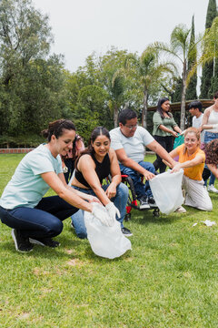 Group of diverse Latin people collecting trash in a public park in Mexico, Latin America. Group of multi age Hispanic volunteers cleaning up and collecting plastic in save the planet concept