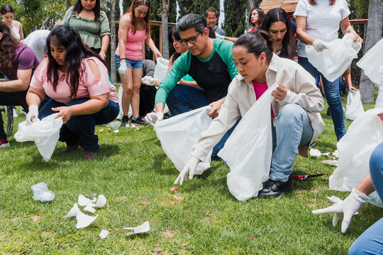 Group of diverse Latin people collecting trash in a public park in Mexico, Latin America. Group of multi age Hispanic volunteers cleaning up and collecting plastic in save the planet concept