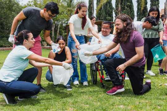 Group of diverse Latin people collecting trash in a public park in Mexico, Latin America. Group of multi age Hispanic volunteers cleaning up and collecting plastic in save the planet concept