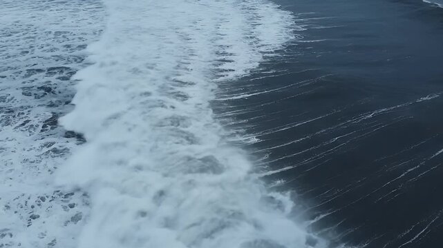 Dynamic ocean waves crashing with foamy crests under a dark sky