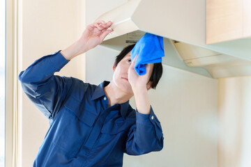 レンジフードを掃除をする家事代行の男性 © taka