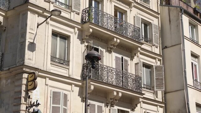 Haussmann style building showcasing balconies, windows, and a classic street lamp on a sunny day