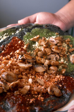 Person holding a plate of Mexican artisanal blue corn gordita with sauteed mushrooms and salsa