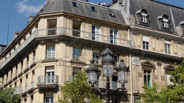 Traditional Parisian Haussmann building featuring balconies, attic windows, and a decorative street lamp