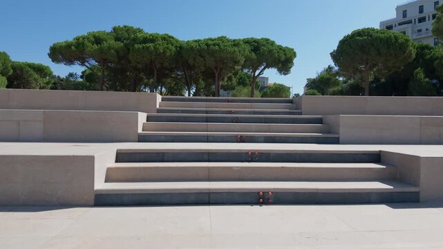 Wide stone steps rising through a park with tall pine trees and a white building beyond, Juan-les-Pins, France