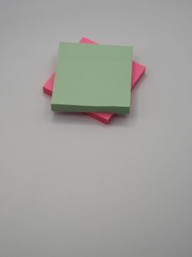 Stacked colourful adhesive notes with a green sheet positioned on top of pink notes. Providing the concepts workplace planning, organisation, communication, and creative brainstorming