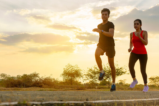 Silhouette of couple running together on road with sunset background.. Couple, fit runners fitness runners jogging together during outdoor workout