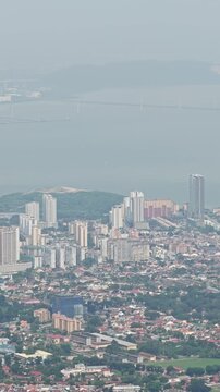 Aerial panning view of Penang coastal city, George Town, featuring Homo sapiens settlements near ocean and tropical foliage, Malaysia