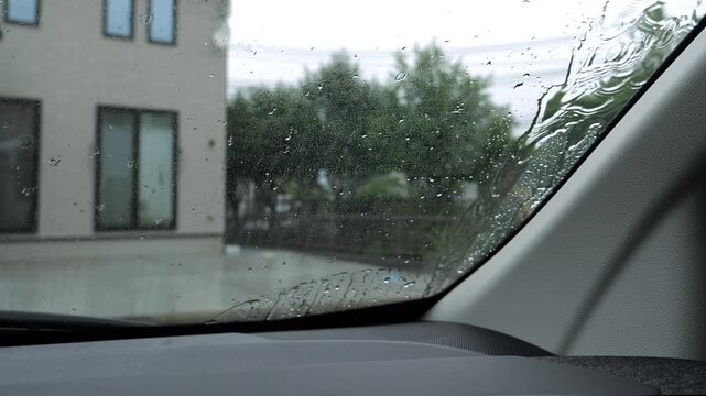 Car windshield wipers clearing rain drops off the glass on a rainy day