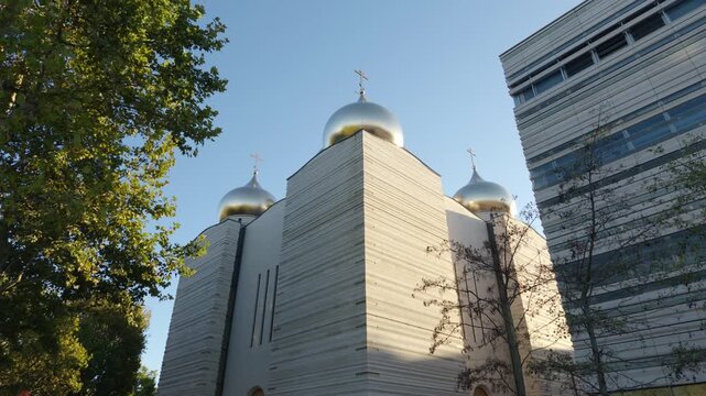 Holy Trinity Cathedral with golden domes contrasting against a modern building in Paris