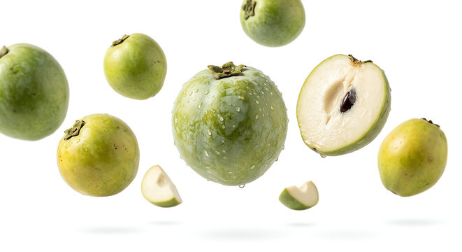 Fresh green sapodilla fruits, whole and halved, suspended mid-air