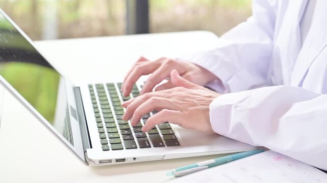 A doctor&rsquo;s hands as they enter electronic medical records on a laptop; an image of the digitization of the healthcare setting and medical records