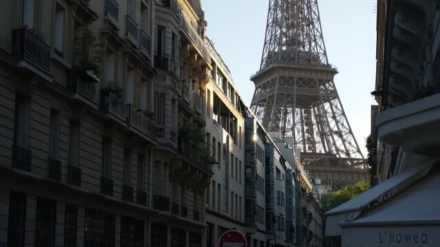 Paris street showing classic buildings and the Eiffel Tower against a bright sky