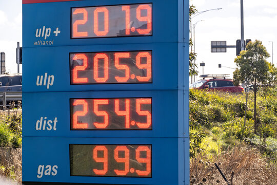 A petrol station price board displaying fuel prices in cents per litre for unleaded plus ethanol, unleaded, diesel, and gas in Melbourne, Victoria, Australia, with LED digital numbers. Cost of living