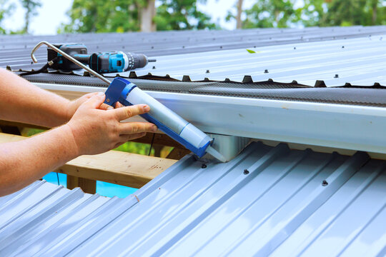 Man applying sealant on metal roof during construction work