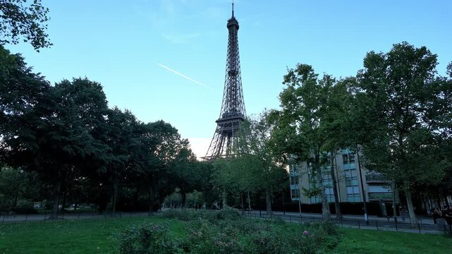 Eiffel Tower landmark standing over green park trees with a clear sky in Paris