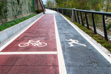 Fototapeta premium Urban bicycle and running lanes with clearly marked pavement symbols. Modern pathway features dedicated spaces for cycling, jogging, walking, fitness, recreation, active transportation, representing.