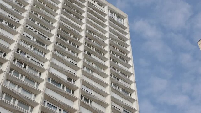 Concrete facade of a high rise residential building with many windows under a blue sky
