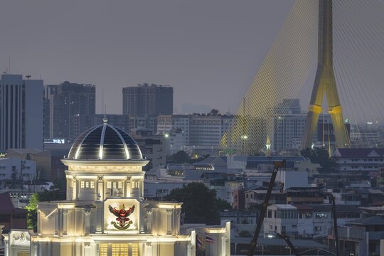 The Royal Thai Survey Department, neoclassical architecture with Garuda emblem (Phra Khrut Pha), the national emblem of Thailand, behind it the Rama VIII Bridge over the Mae Nam Chao Praya, Bangkok, Thailand