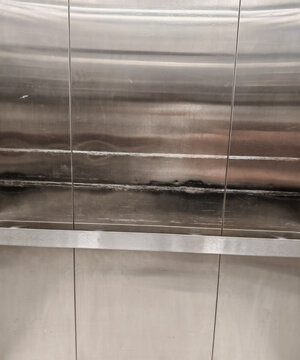 brushed stainless steel elevator wall panels and metal handrail. Target commercial architectural backgrounds, modern industrial aesthetic layouts, and building interior design templates.