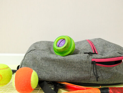 Gyroscopic wrist trainer Powerball next to a tennis racket and tennis balls. Sports equipment for grip strength, wrists, and forearms, suitable for tennis training
