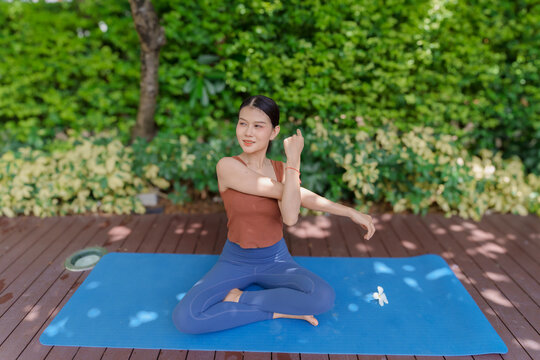 Asian Gen Z woman stretching shoulders representing wellness self care flexibility and active healthy lifestyle.