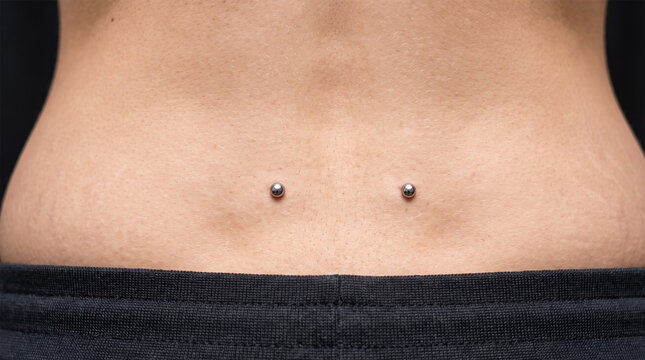Close Up of Woman Lower Back with Symmetrical Double Venus Dimple Dermal Piercings