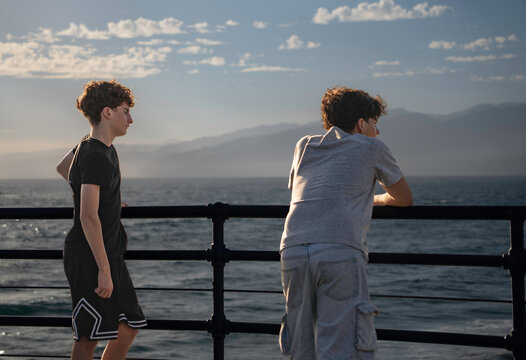 Two boys enjoying a moment of reflection and friendship by the sea