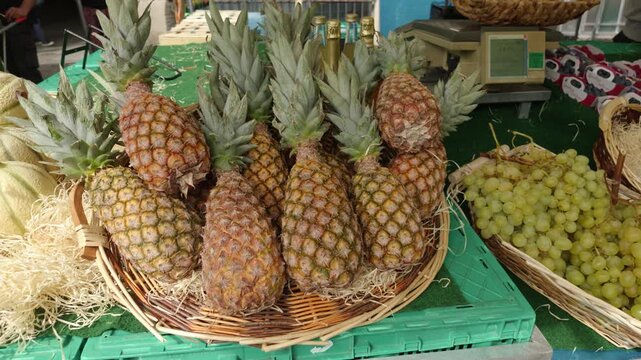 Fresh pineapples and green grapes filling baskets at an outdoor fruit market