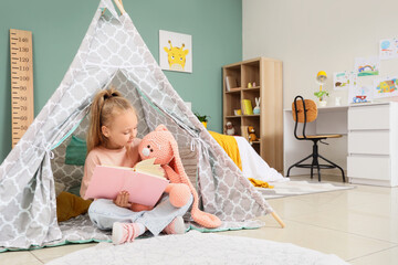 Childhood education and imagination, young girl reading a book with a plush toy inside a play tent in a cozy bedroom for creative learning development © Pixel-Shot