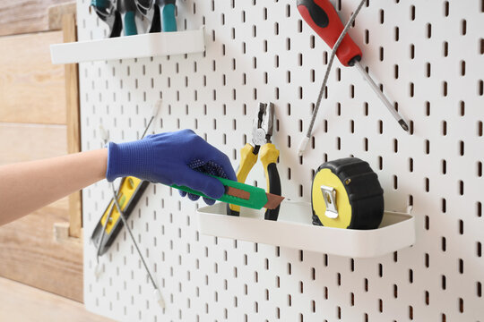 Home improvement and diy project, person wearing protective gloves organizing tools on a pegboard wall for renovation and construction work