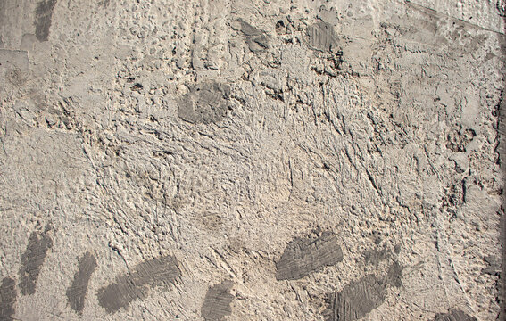 Rough concrete wall with weathered plaster finish and dark marks. Ideal for industrial backgrounds, architectural design backdrops, grunge textures, and surface finishes.
