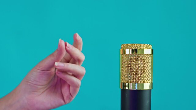 Close-up of finger snapping action near professional microphone in recording studio setting
