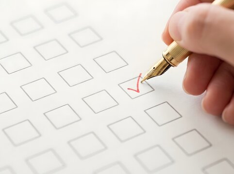 Hand marking a red checkmark in a checkbox with a gold fountain pen